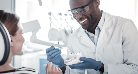 Doktor gigi sedang bercakap dengan pesakitnya sambil tersenyum