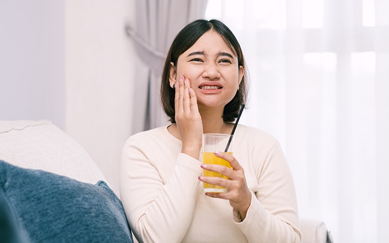 Dentist holding a toothbrush demonstrating sensitive teeth causes