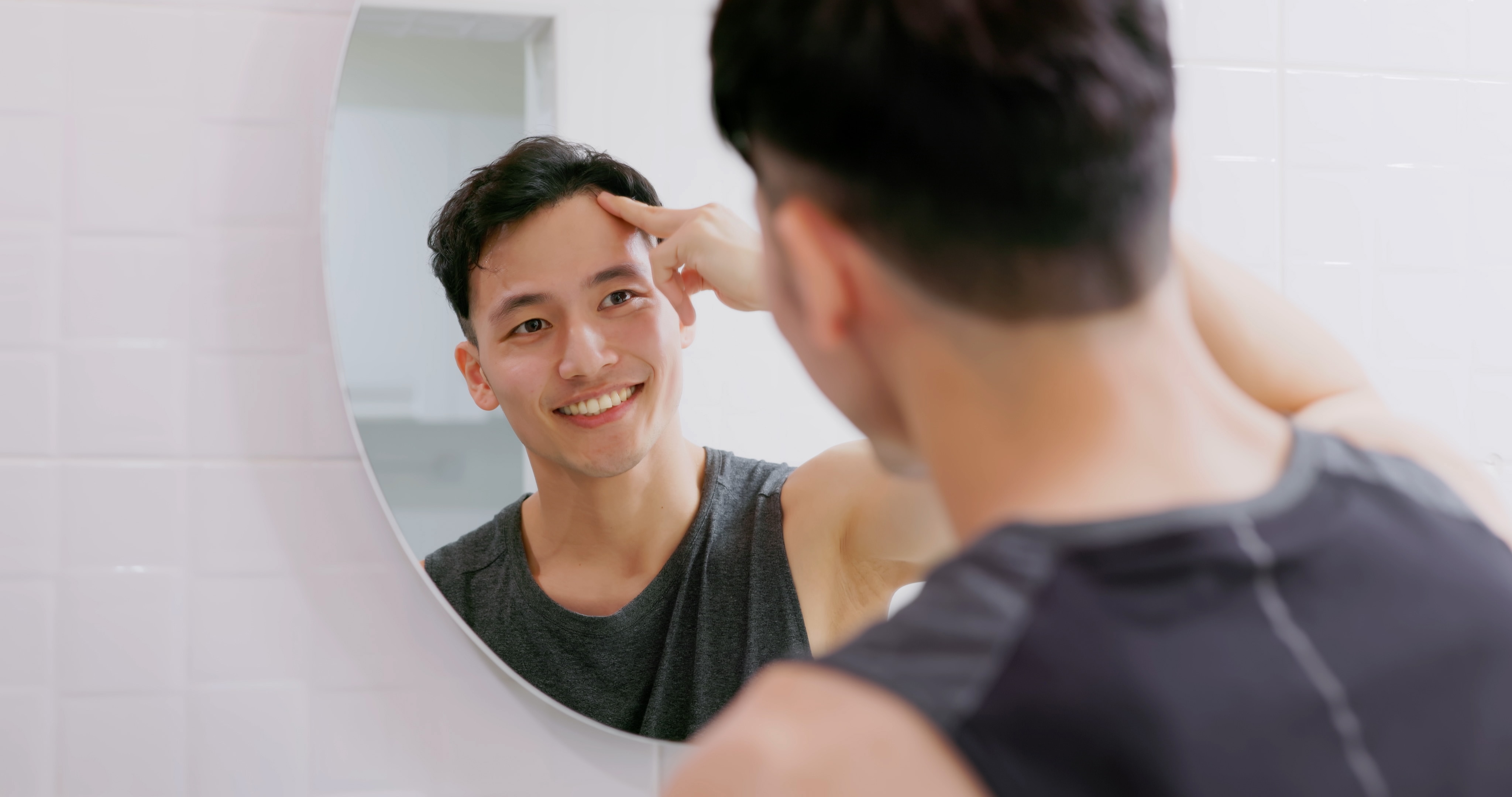 Young man happily looks in the mirror after using home remedies for gum pain