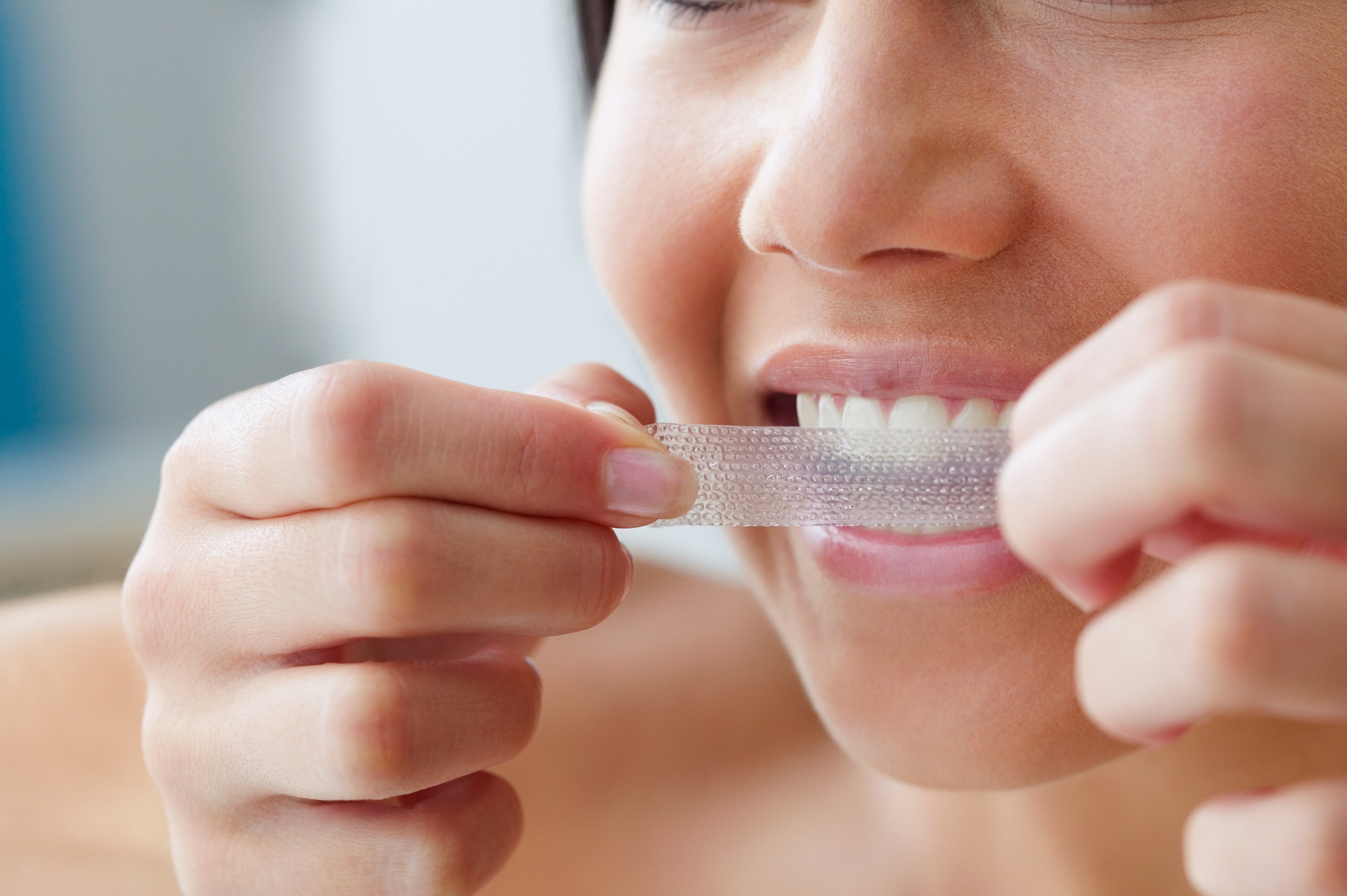 Woman wearing red sweater, demonstrating how to whiten teeth 