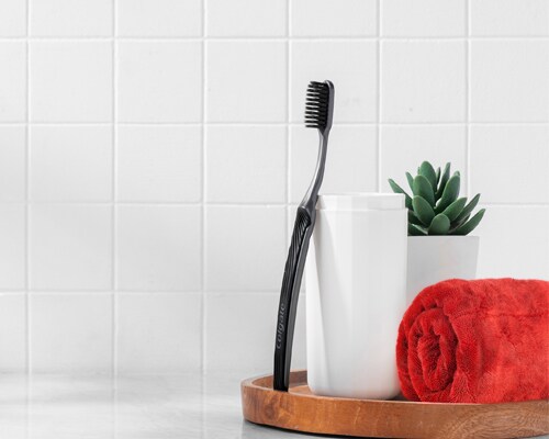 Sikat Gigi Colgate SlimSoft Charcoal bersandar pada cangkir
