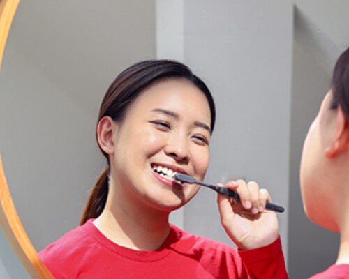 Wanita Asia menyikat giginya dengan Sikat Gigi Colgate SlimSoft Charcoal